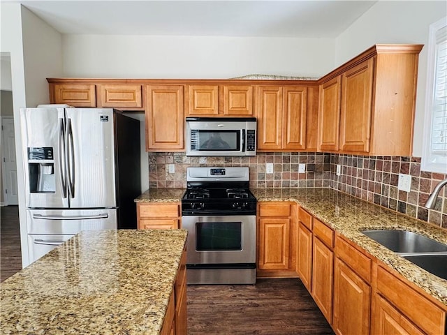 kitchen with light stone countertops, tasteful backsplash, stainless steel appliances, sink, and dark hardwood / wood-style floors