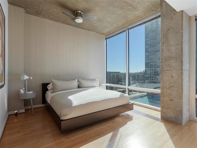 bedroom featuring expansive windows, ceiling fan, and light hardwood / wood-style flooring