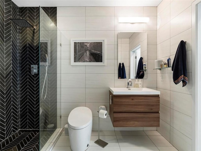 bathroom featuring a tile shower, tile walls, vanity, toilet, and tile patterned floors