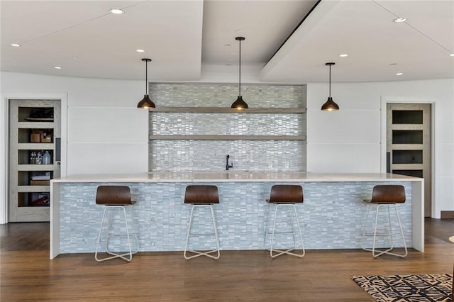 bar with hanging light fixtures and hardwood / wood-style floors