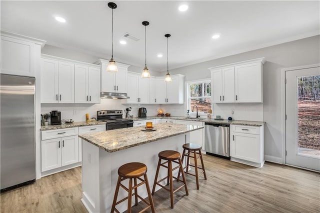 kitchen with stainless steel appliances, white cabinetry, a kitchen island, and a kitchen breakfast bar