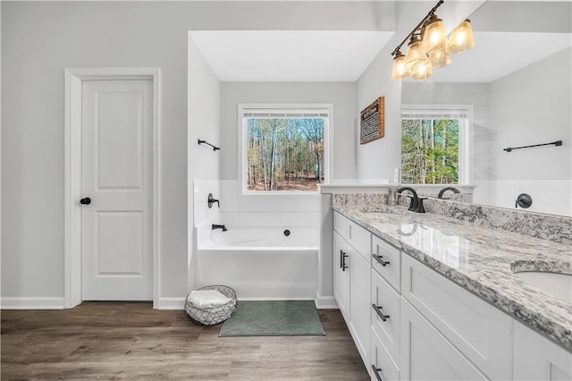 bathroom featuring vanity, a notable chandelier, hardwood / wood-style flooring, and a bathing tub