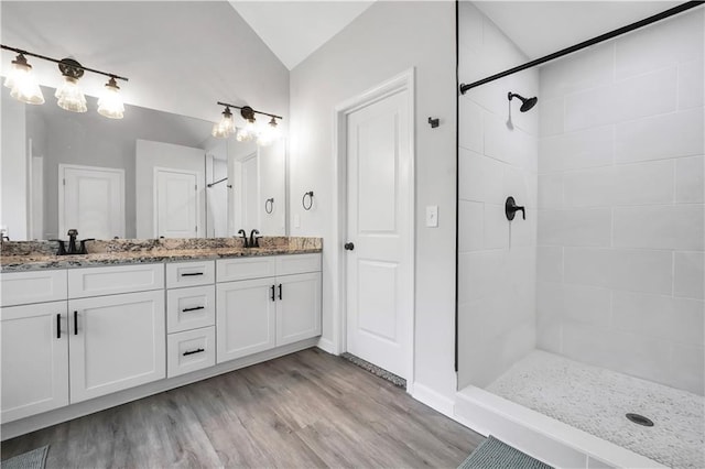 bathroom featuring vanity, lofted ceiling, hardwood / wood-style floors, and a tile shower