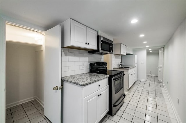 kitchen with white cabinetry, stainless steel appliances, backsplash, and light tile patterned floors