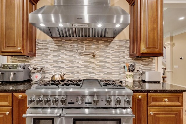 kitchen featuring exhaust hood, range with two ovens, brown cabinets, backsplash, and ornamental molding