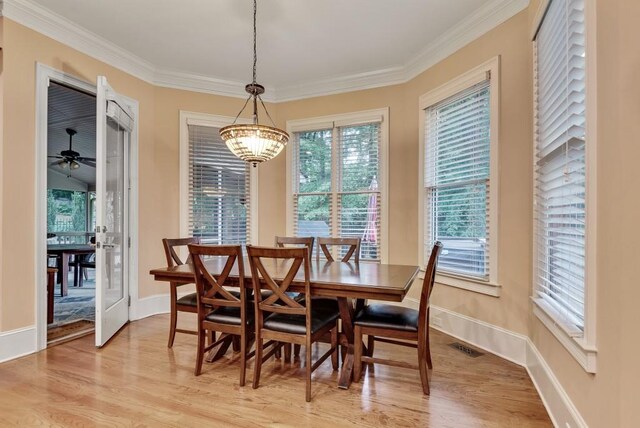 dining room featuring light wood-style flooring, ornamental molding, baseboards, and a chandelier