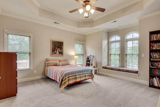carpeted bedroom with a raised ceiling, ornamental molding, baseboards, and a ceiling fan