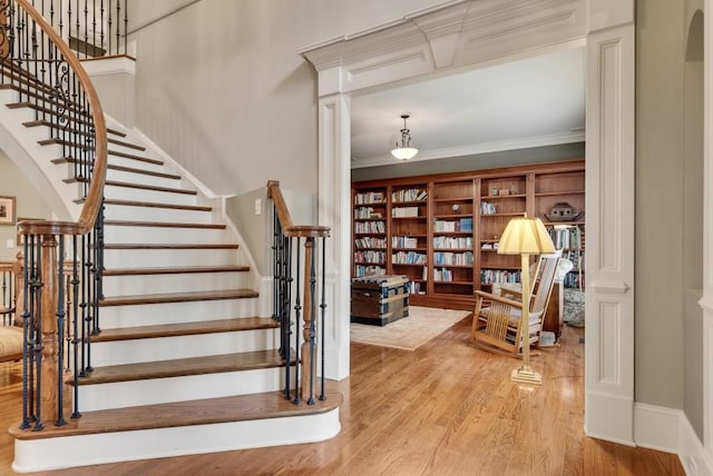 stairs featuring wood finished floors, arched walkways, and crown molding