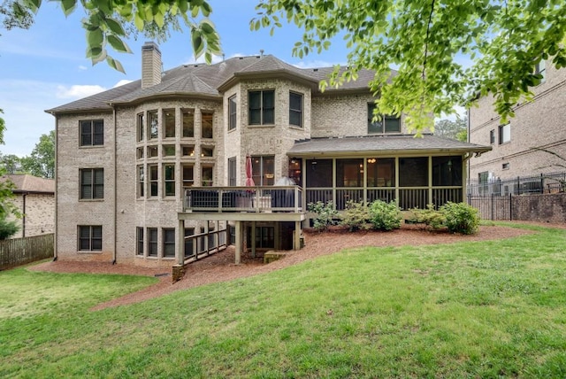 back of property featuring a sunroom, a chimney, brick siding, and a wooden deck