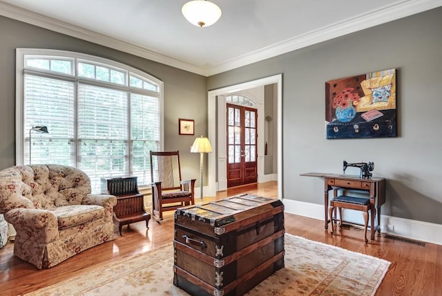 living room with ornamental molding, light wood-type flooring, and baseboards