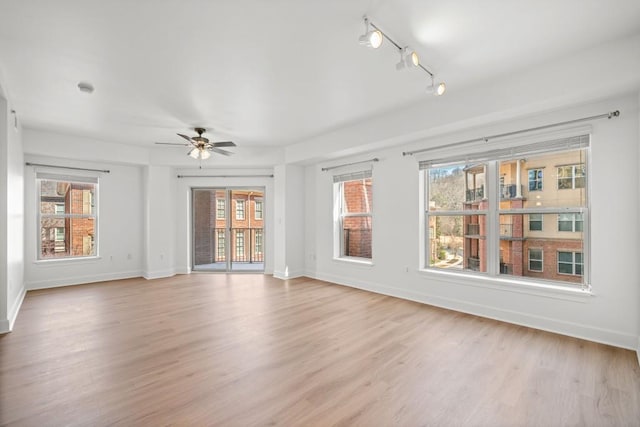 unfurnished room featuring rail lighting, ceiling fan, light wood-style flooring, and baseboards