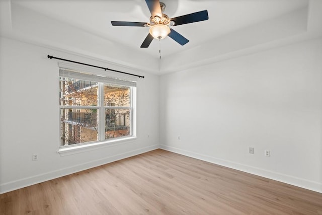 spare room with a ceiling fan, light wood-style flooring, and baseboards