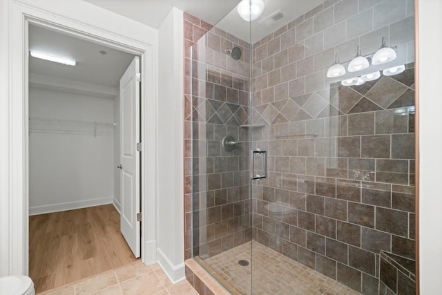 bathroom featuring a spacious closet, a shower stall, and visible vents