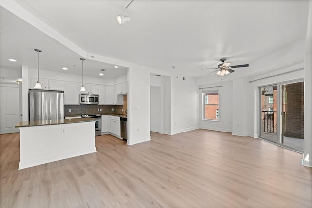 kitchen featuring tasteful backsplash, appliances with stainless steel finishes, white cabinetry, light wood-type flooring, and baseboards