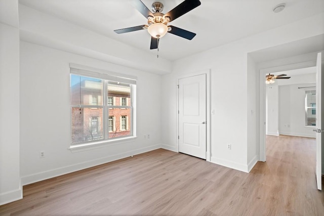 unfurnished bedroom featuring light wood-type flooring, baseboards, and a ceiling fan