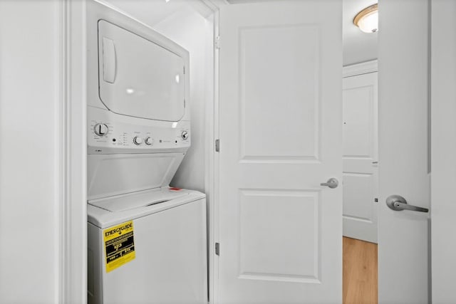 laundry room with laundry area, light wood-type flooring, and stacked washing maching and dryer