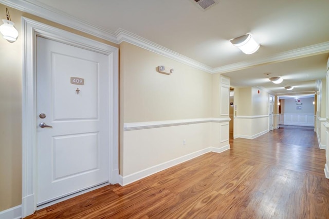 unfurnished room featuring ornamental molding, wood finished floors, visible vents, and baseboards