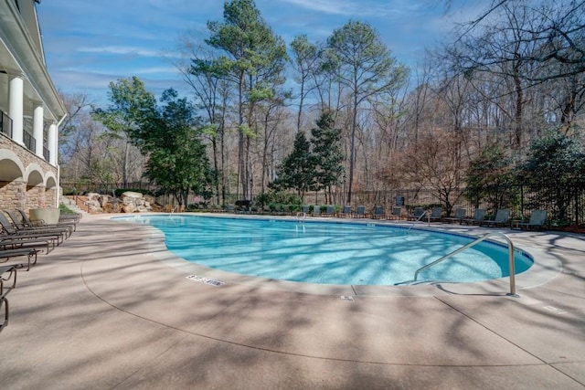 community pool with a patio and fence