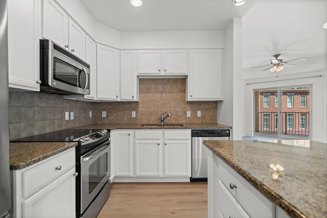 kitchen with white cabinetry, dark stone counters, stainless steel appliances, and a sink