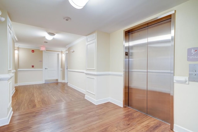 hall with elevator, light wood-style flooring, and baseboards