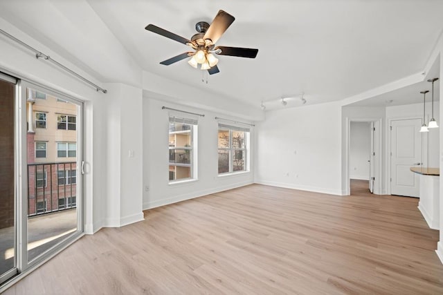 unfurnished living room with light wood finished floors, track lighting, baseboards, and a ceiling fan