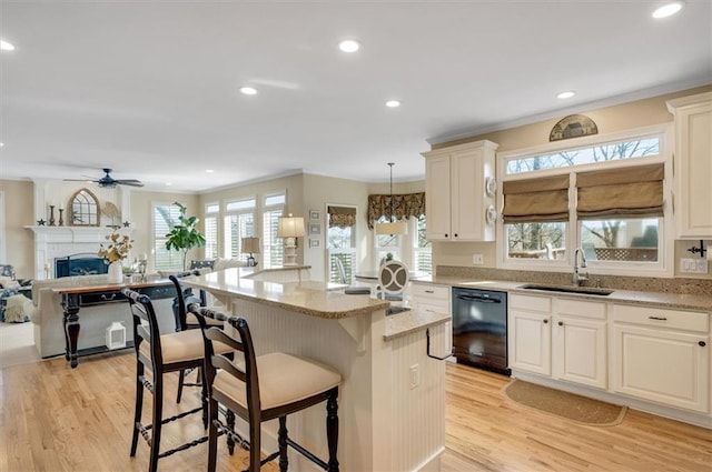 kitchen featuring a center island, open floor plan, dishwasher, a kitchen breakfast bar, and a sink