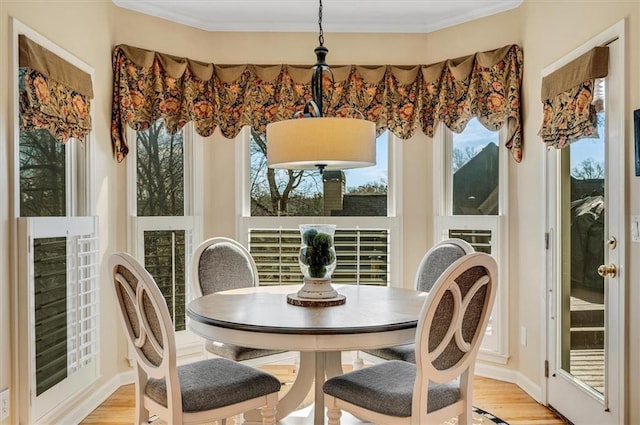 dining area with light wood-type flooring, baseboards, and ornamental molding