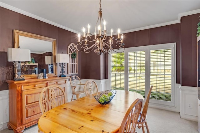 dining room featuring an inviting chandelier, crown molding, a decorative wall, and light carpet