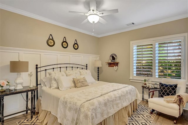 bedroom with a ceiling fan, light wood-style floors, visible vents, and ornamental molding