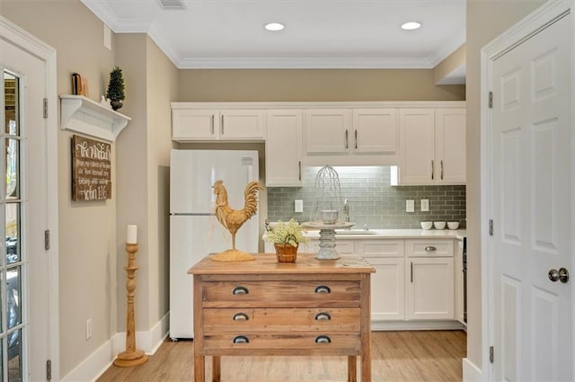 kitchen featuring white cabinetry, crown molding, light wood-type flooring, and freestanding refrigerator