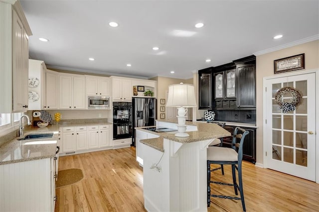 kitchen with a center island, light wood-type flooring, appliances with stainless steel finishes, a kitchen breakfast bar, and a sink