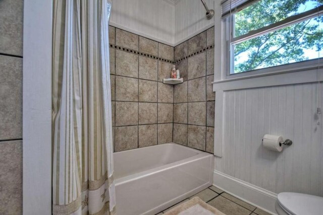 bathroom featuring shower / tub combo with curtain, toilet, and tile patterned flooring