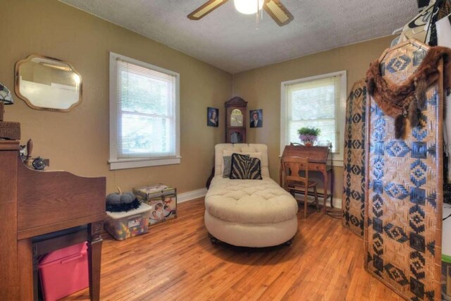 sitting room featuring light hardwood / wood-style floors, a textured ceiling, a baseboard heating unit, and ceiling fan