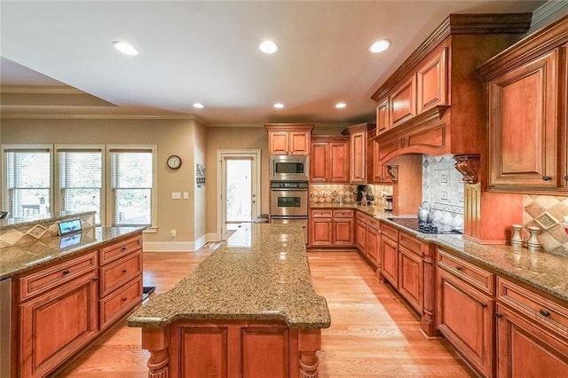 kitchen with stainless steel microwave, decorative backsplash, a center island, and light wood-type flooring