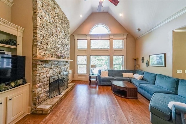 living room featuring a fireplace, hardwood / wood-style flooring, ceiling fan, high vaulted ceiling, and ornamental molding