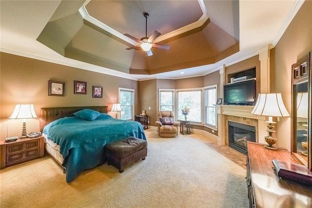 bedroom featuring a fireplace, a raised ceiling, carpet floors, ceiling fan, and crown molding