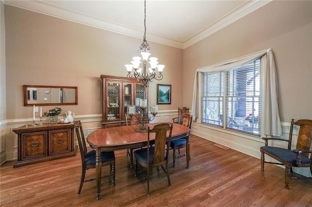 dining room with crown molding, wood-type flooring, and an inviting chandelier