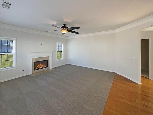 unfurnished living room with a fireplace with flush hearth, visible vents, baseboards, and crown molding