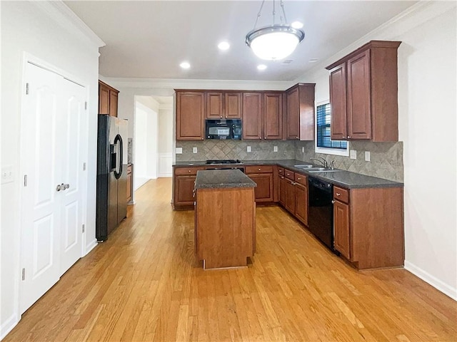 kitchen featuring a sink, light wood-style floors, backsplash, a center island, and black appliances