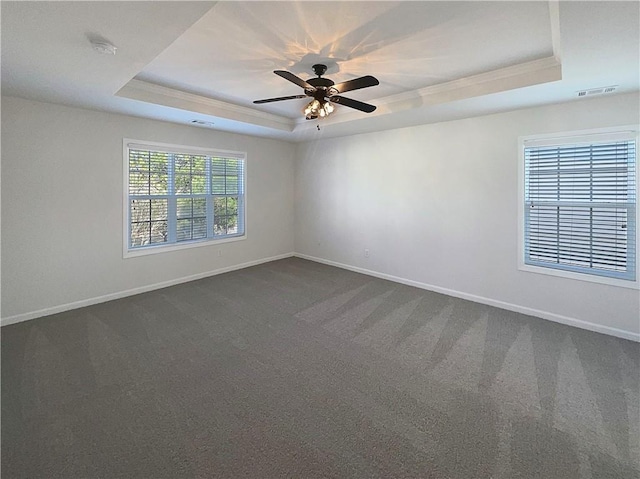 unfurnished room featuring visible vents, a tray ceiling, and baseboards