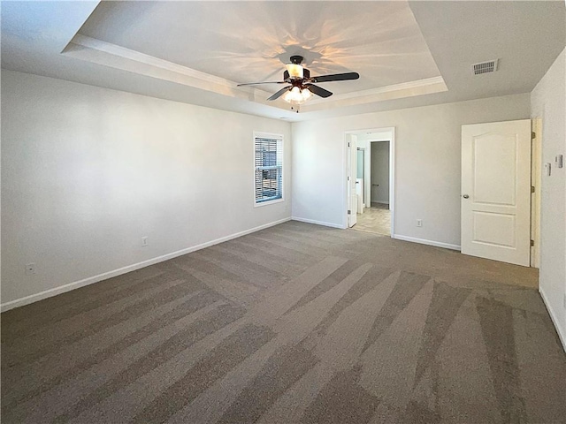 unfurnished bedroom featuring baseboards, visible vents, a ceiling fan, a tray ceiling, and carpet floors