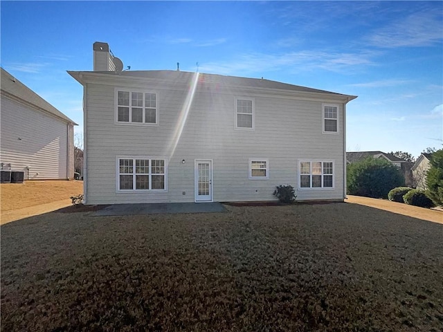 back of property featuring a patio, a lawn, a chimney, and central air condition unit