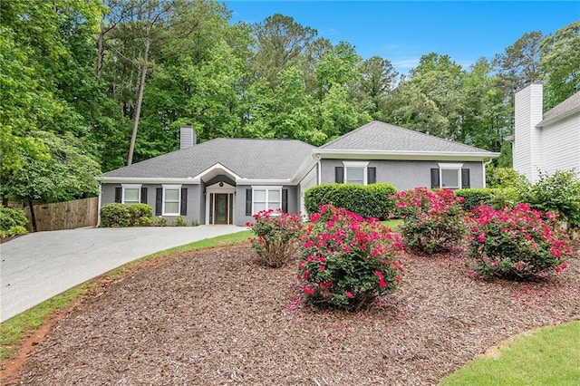 ranch-style home with a chimney, fence, and driveway