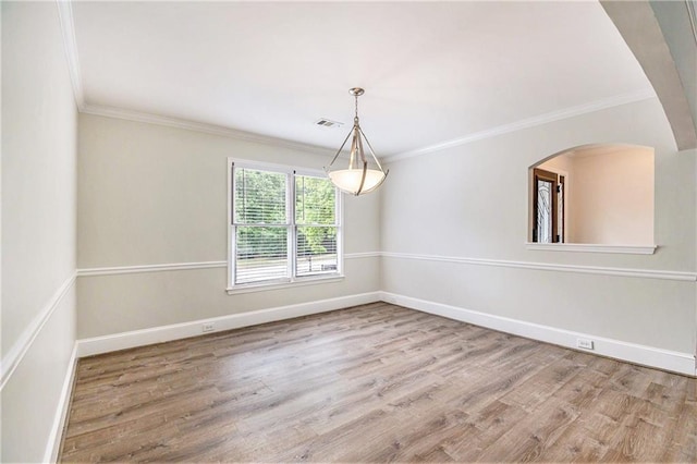 spare room with wood finished floors, crown molding, baseboards, and arched walkways