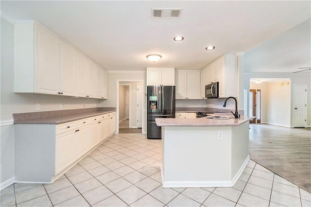 kitchen featuring refrigerator with ice dispenser, a sink, a peninsula, light tile patterned floors, and baseboards