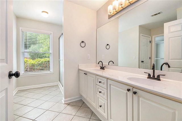 full bath featuring baseboards, tile patterned flooring, double vanity, and a shower with door
