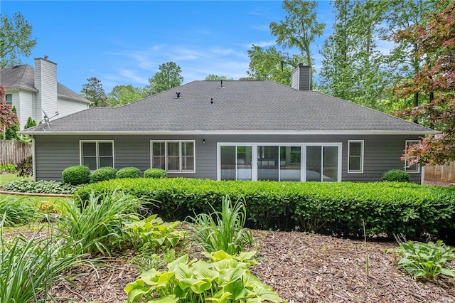 back of property featuring fence, a chimney, and a shingled roof
