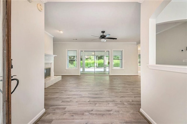unfurnished living room featuring ornamental molding, baseboards, a ceiling fan, and plenty of natural light