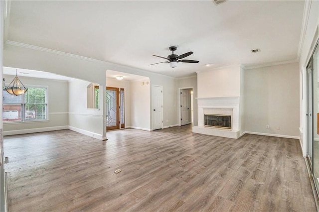unfurnished living room featuring wood finished floors, baseboards, ornamental molding, a ceiling fan, and a glass covered fireplace