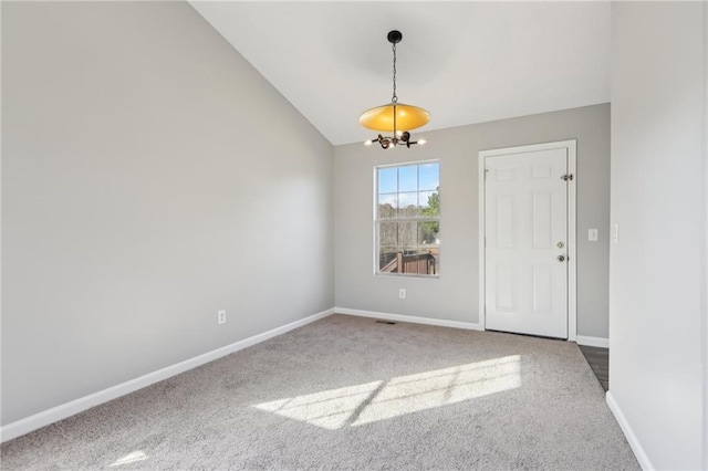 carpeted empty room featuring lofted ceiling and a chandelier